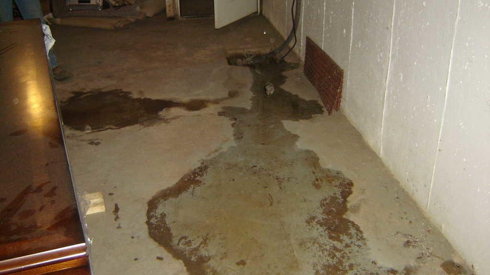 Standing water spread across a basement floor after a plumbing leak